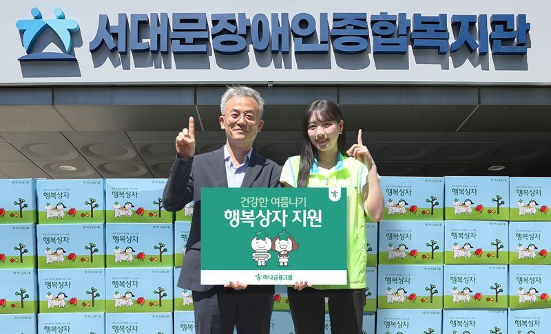 하나금융그룹이 이어지는 폭염으로 어려움을 겪는 장애인과 장애인 가족을 돕기 위해 폭염 대비 물품이 담긴 '건강한 여름나기 행복상자' 1111개를 전달했다. 이날 행사에 참석한 하나금융 직원이 송용성 서대문장애인종합복지관장(왼쪽)에게 행복상자를 전달하며 기념촬영을 하고 있다. [사진제공 하나금융지주] 