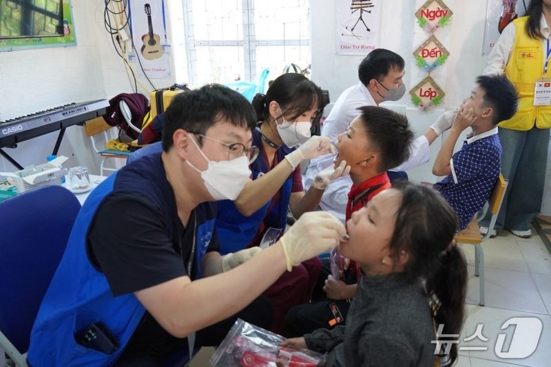 분당제생병원 치과 의료진과 베트남 현지 의료진이 어린이 구강상태를 살피고 불소도포를 하고 있다.[사진제공 분당제생병원]