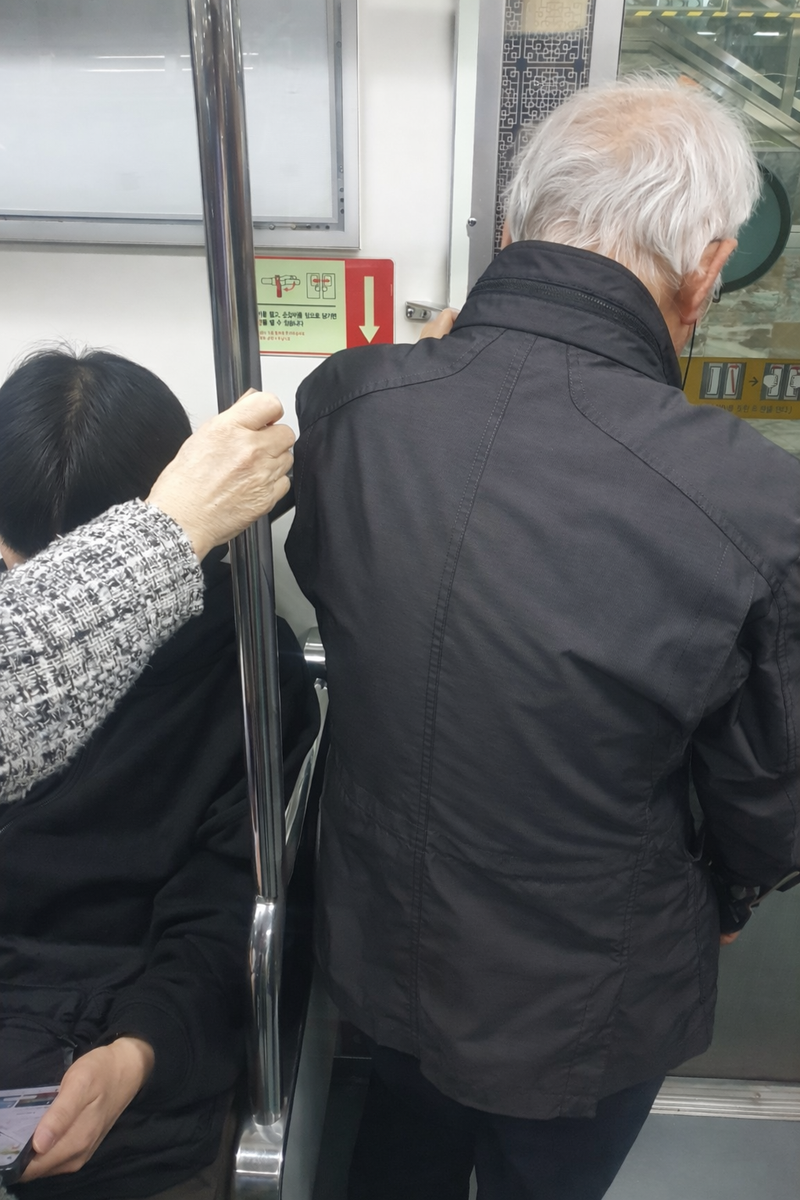 수도권 지하철 객차 내부 모습. 노인이 서 있고 청년이 좌석에 앉아 있다. [사진 성연주 기자]