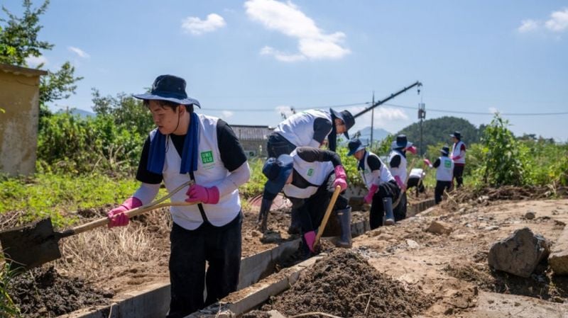  유니클로 임직원들이 지난달 26일 경남 거제 수해 현장을 찾아 침수 지역에 쌓인 토사를 걷어내고 배수로를 정비하고 있다. [사진제공 유니클로]