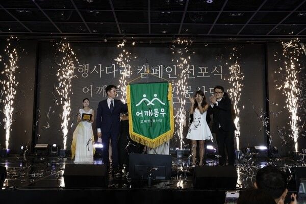 윤종기 어깨동무 연예인봉사단 상임고문(왼쪽)과 박형석 단장이 8일 서울 영등포구 중소기업중앙회 KBIZ홀에서 열린 창단식에서 봉사단 단기를 공개하고 있다. ( 어깨동무 연예인봉사단 )
